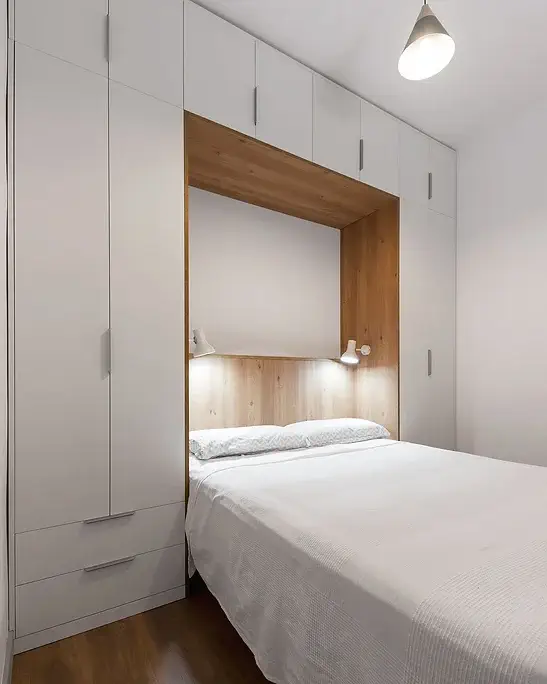 Quarto minimalista com cama embutida e prateleiras iluminadas