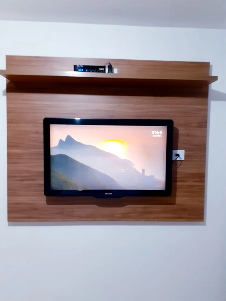 Televisão de tela plana montada em painel de madeira com imagem de pôr do sol