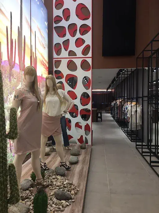 Loja com manequins vestidos e cactos decorativos ao fundo