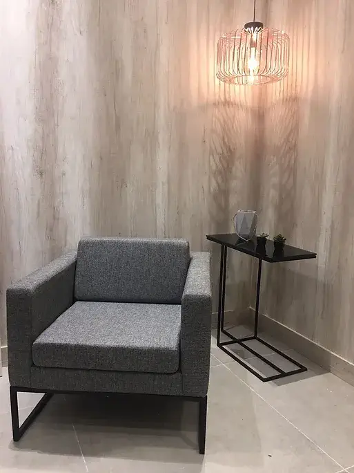 Poltrona cinza com mesa lateral em ambiente minimalista